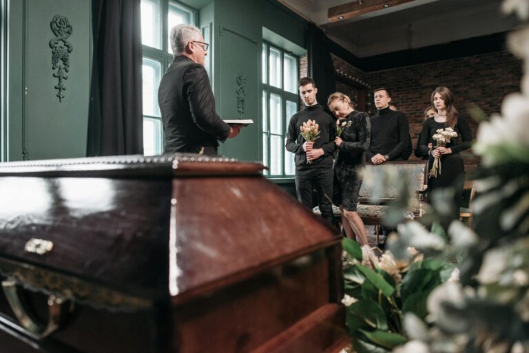 Attendees pay final respects at a solemn funeral ceremony indoors.